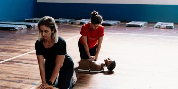 Duas pessoas a praticar técnicas de reanimação em manequins de treino de primeiros socorros